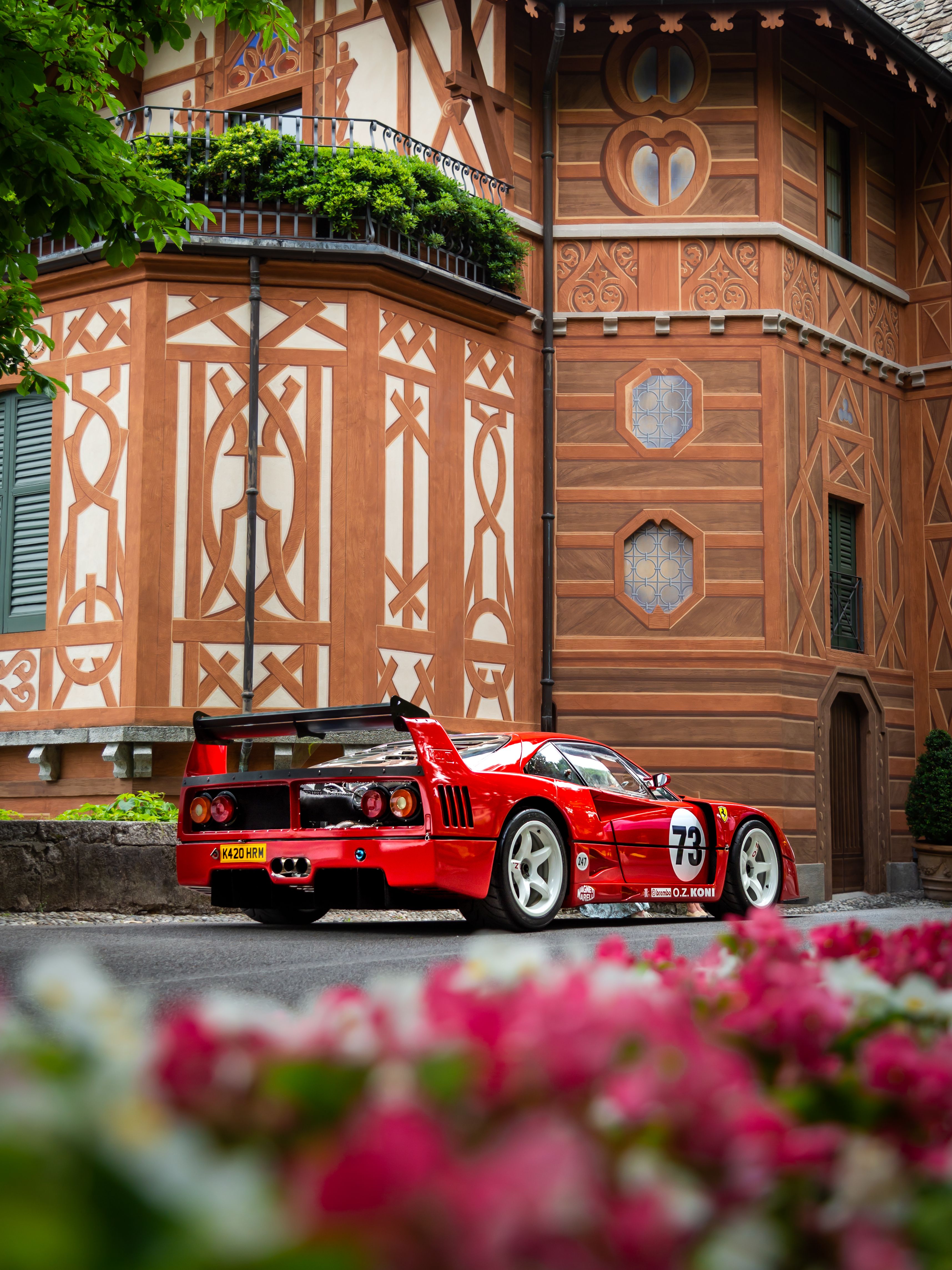 Rear of a red Ferrari F40 parked beside an old brick building